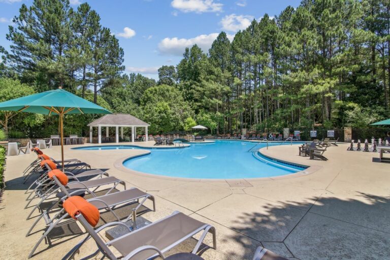 Swimming pool with sundeck and lounge chairs surrounded by native landscaping.